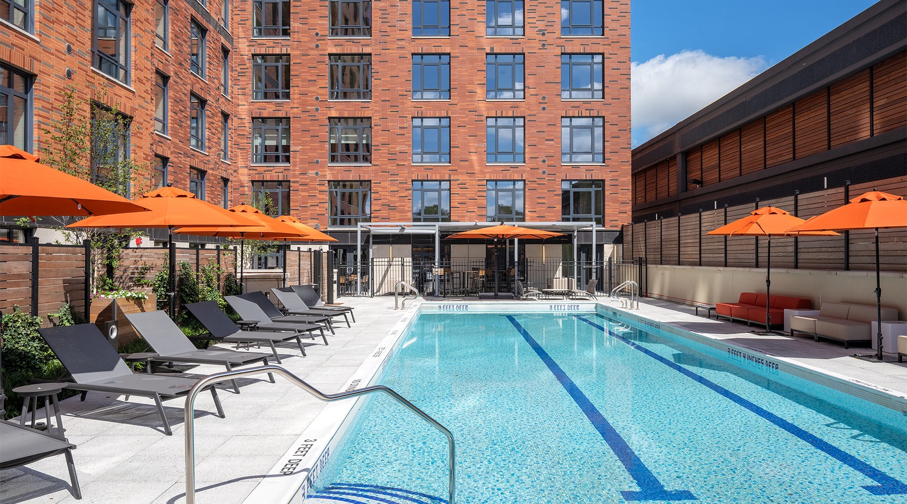 resort style pool with seating with a building behind it